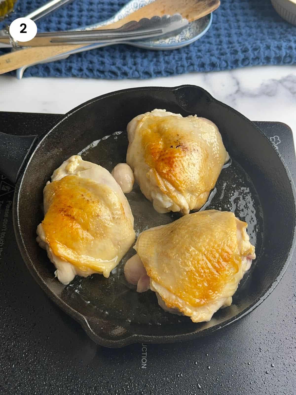 Searing the chicken thighs in cast iron pan.