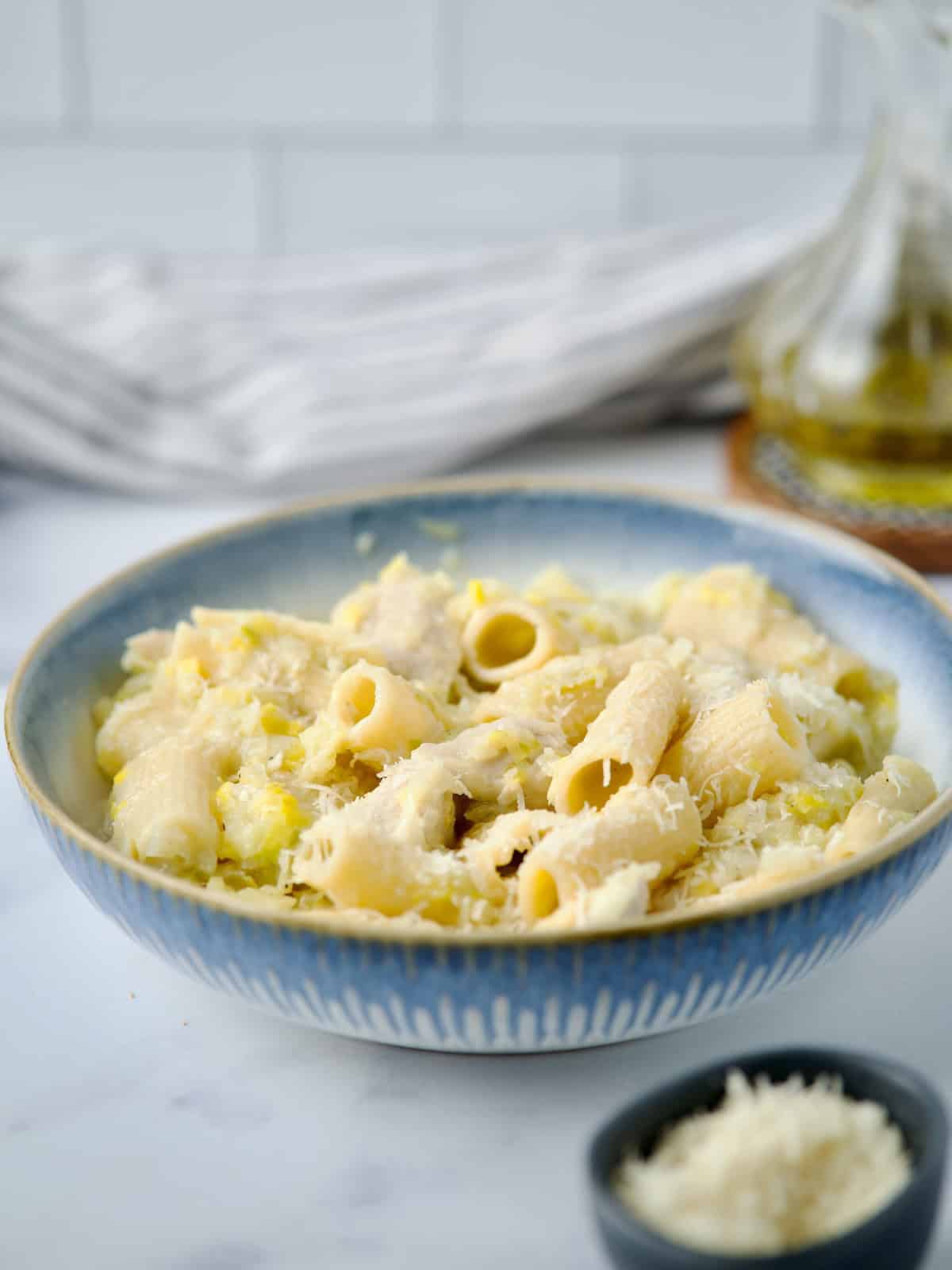 Chicken and leek pasta served in white bowl with parmesan cheese.