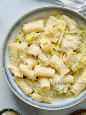 Chicken and leek pasta served in a white bowl with parmesan cheese.