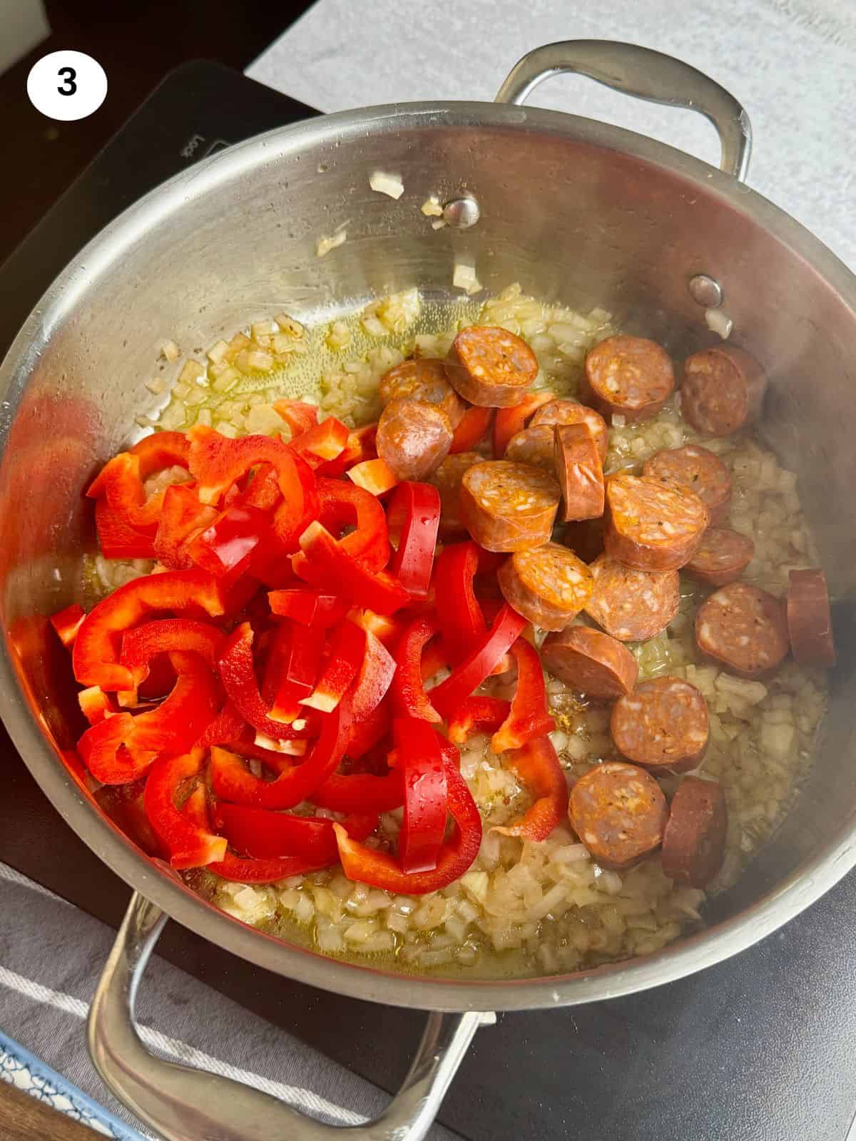 Adding the chorizo and pepper slices to the pan.