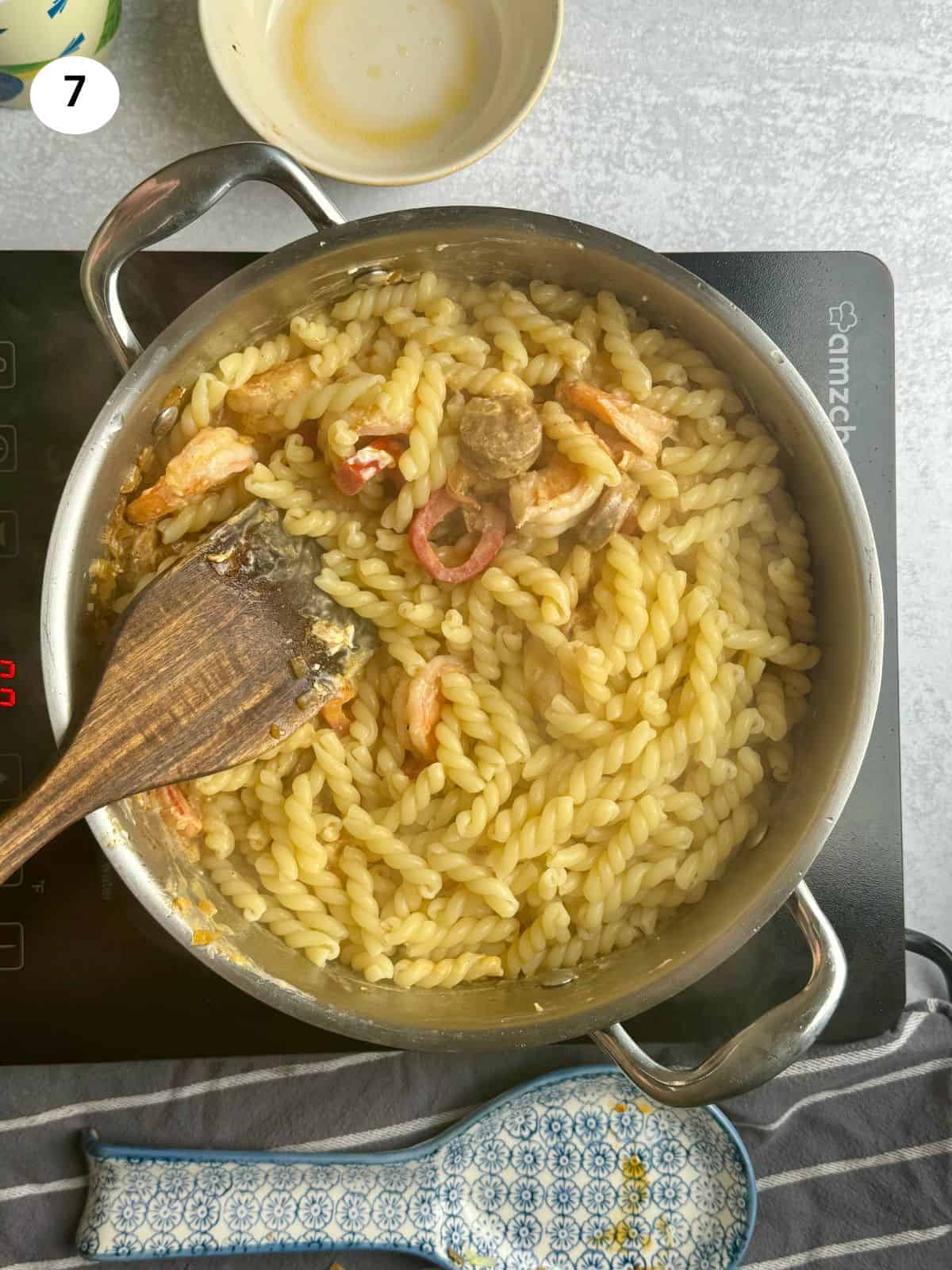 Adding the pasta to the pan.