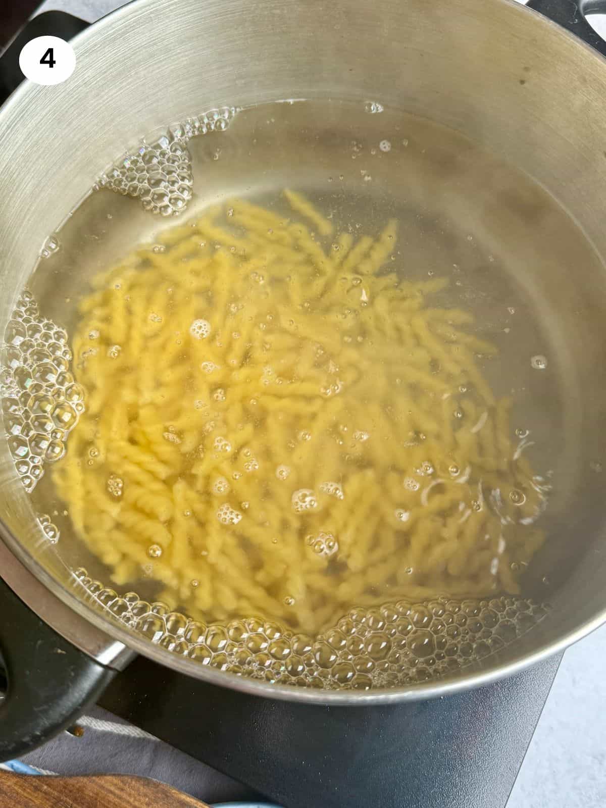 Boiling the gemelli pasta until it is al dente.