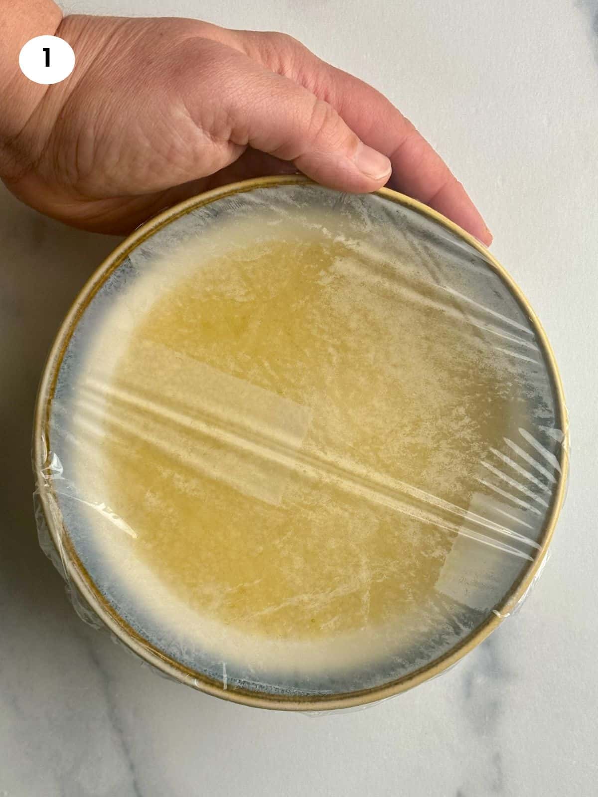 Couscous in a bowl with hot water and covered with cling film.