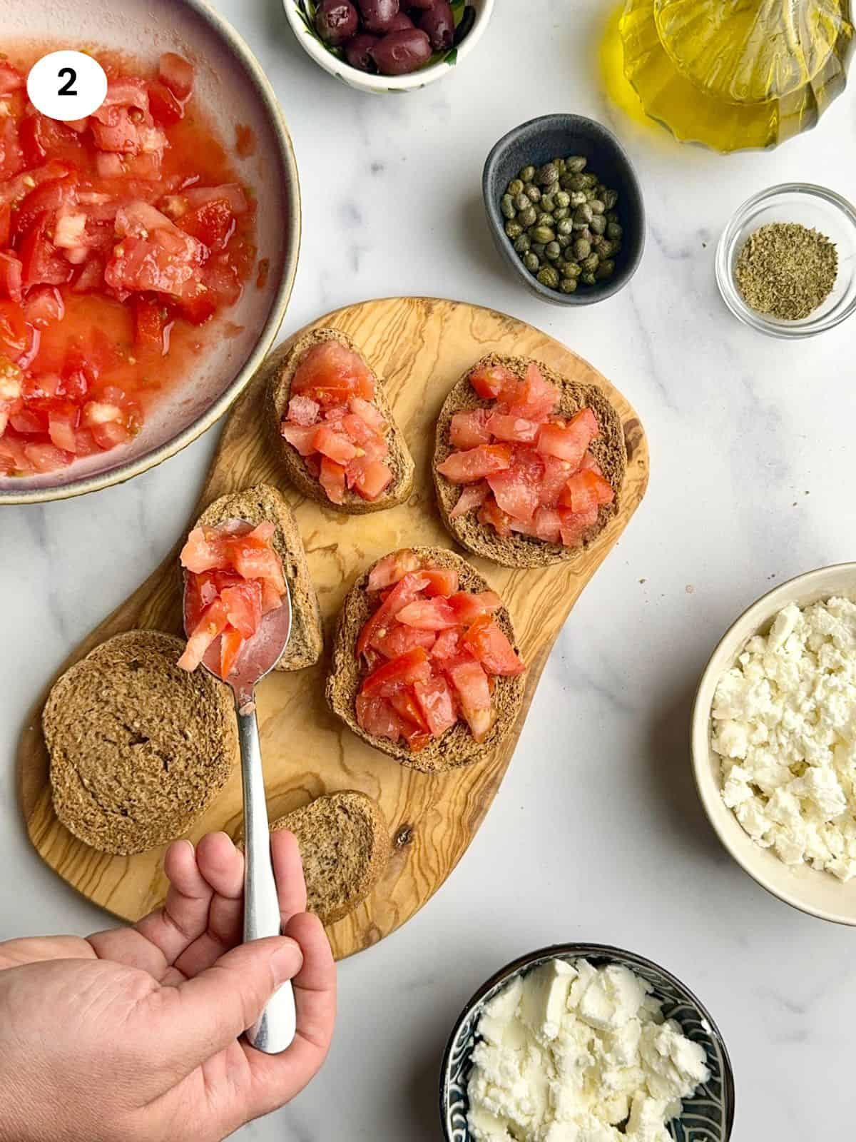 Placing chopped tomatoes on top of each rusk.