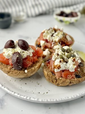 Dakos served on wooden board with olives or capers on them.