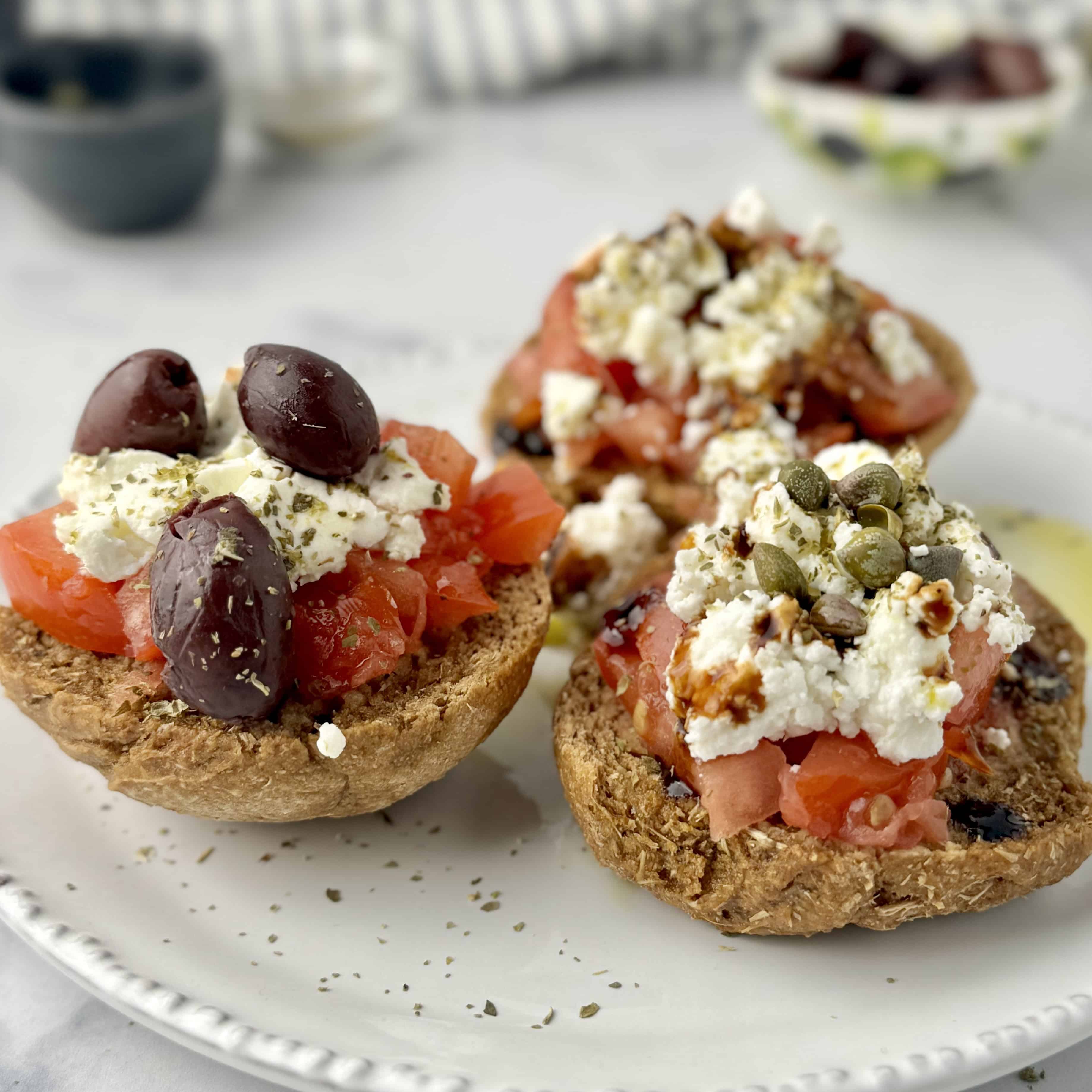 Dakos served on wooden board with olives or capers on them.