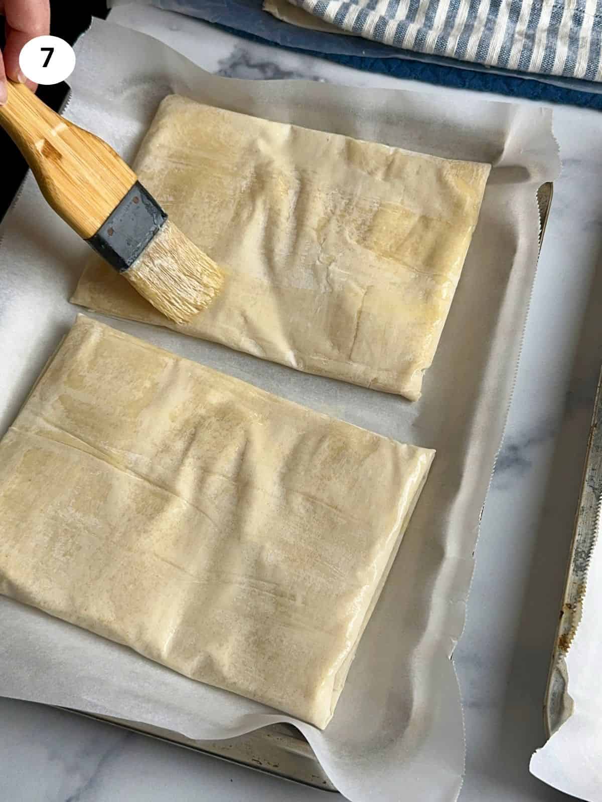 Brushing the top of each parcel with butter.