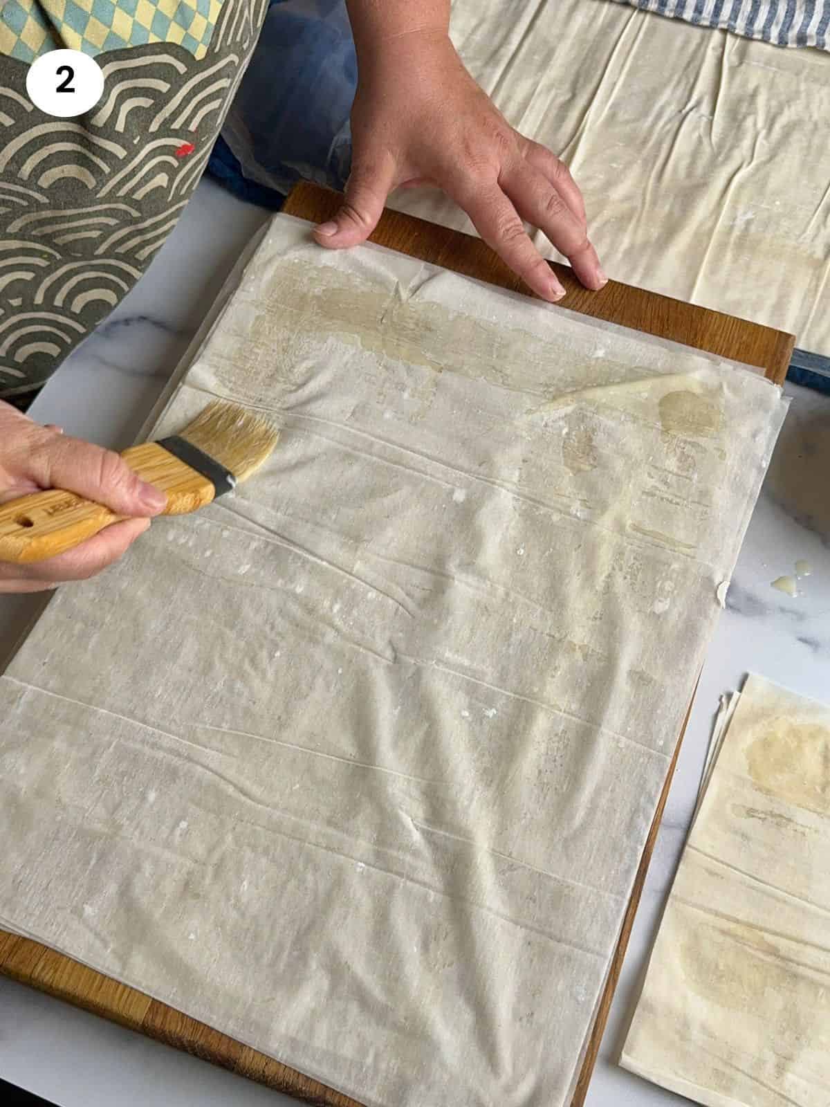 Brushing a phyllo pastry with melted butter.