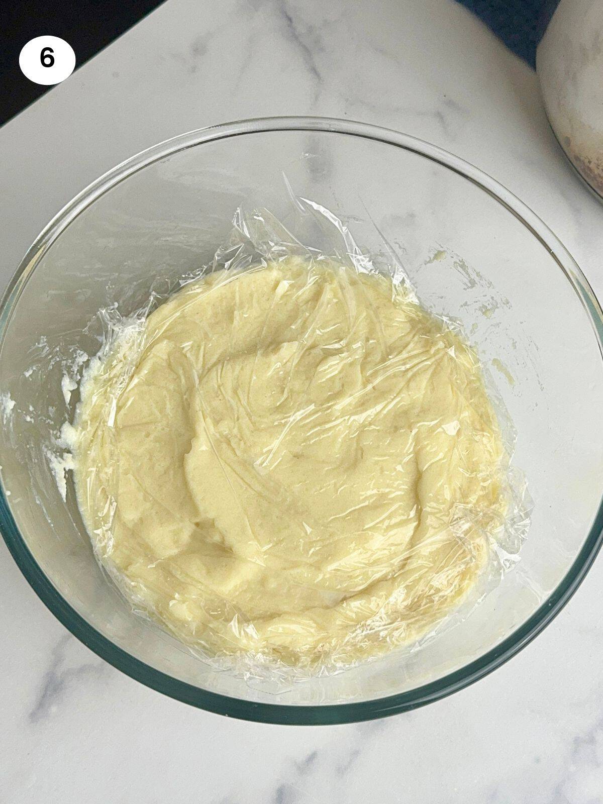 Bougatsa cream cooling down in a bowl covered with cling film.