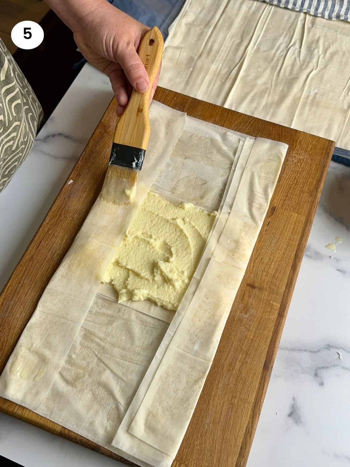 Brushing the long folded sides with butter.