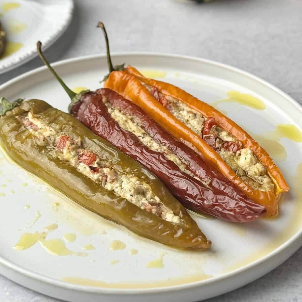 Stuffed peppers with cheeses served in white plate.