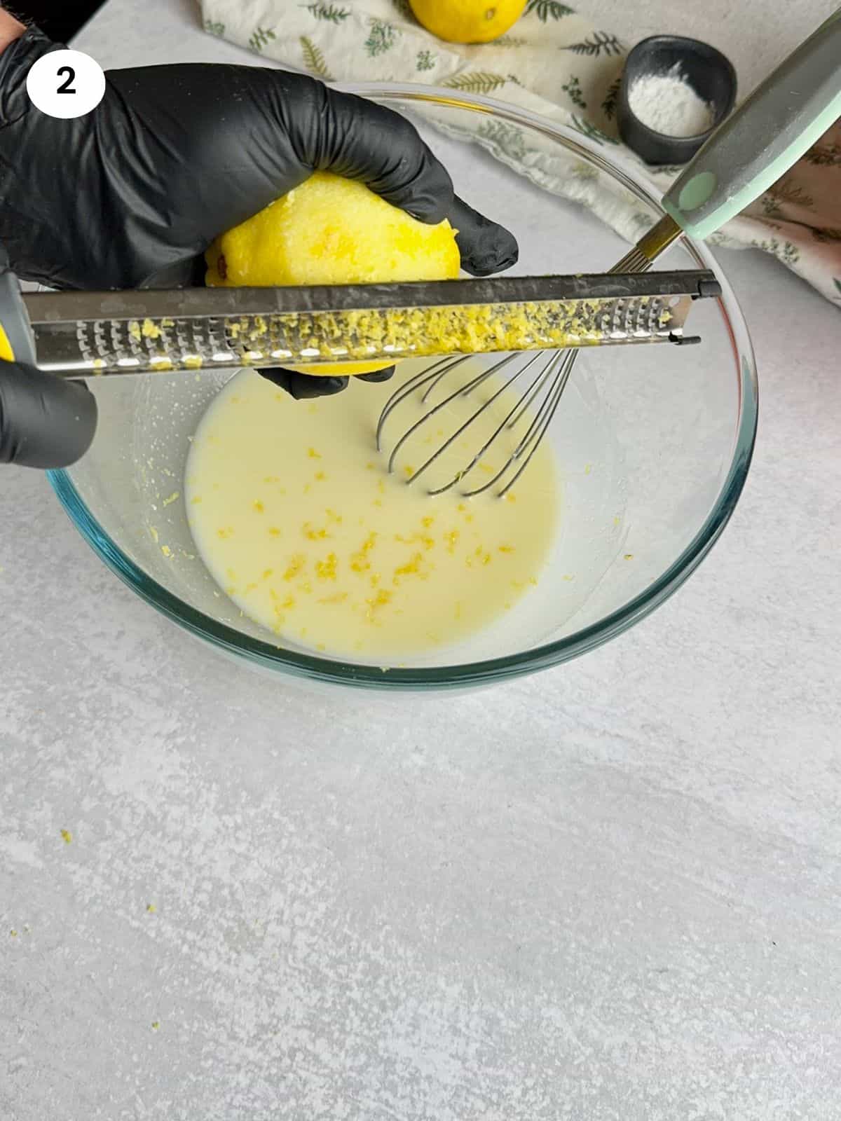 Zesting a lemon and adding it to the mixture.