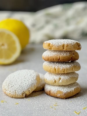 Greek lemon cookies in a stack with lemon in the background.