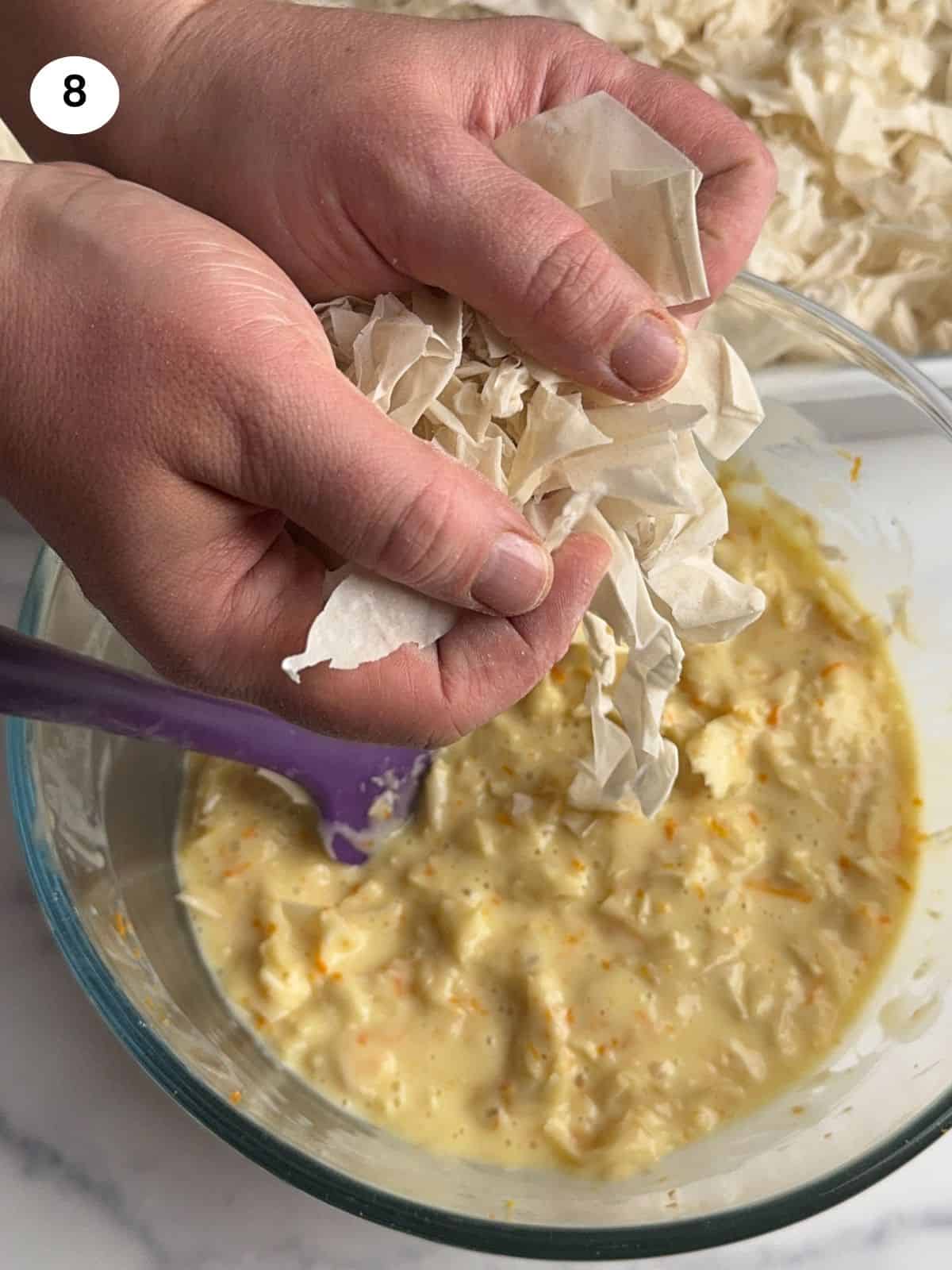 Adding the dried phyllo strips to the batter.