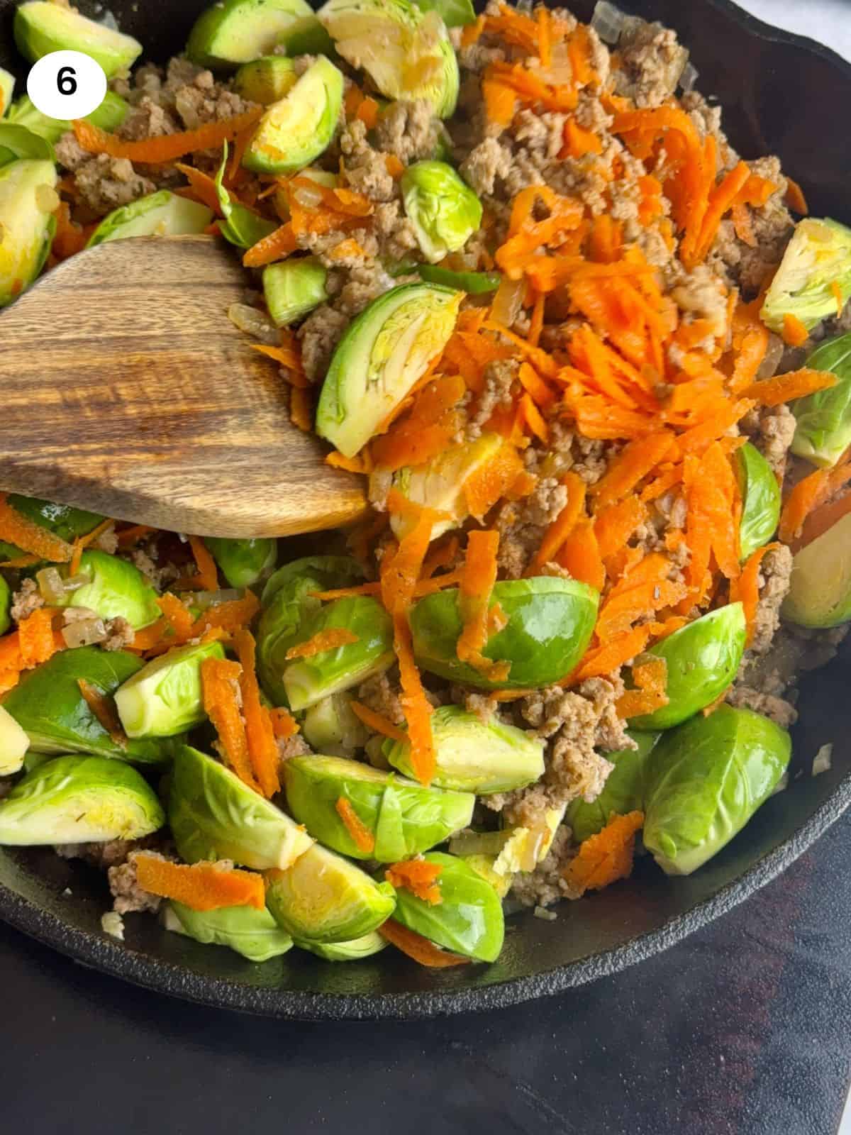 Mixing the brussel sprouts and grated carrot with the ground turkey.