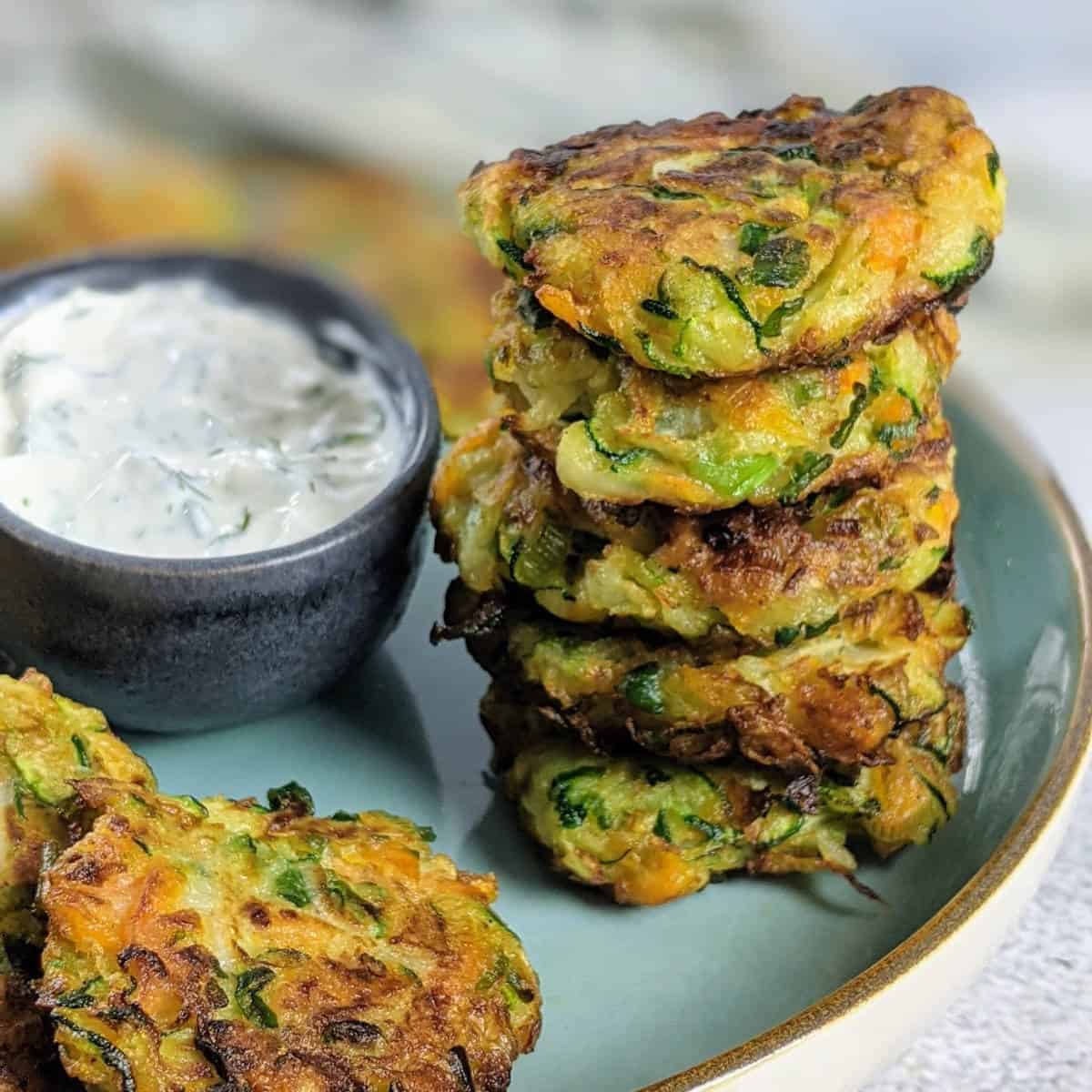 Kohlrabi fritters placed in a circle on a blue plate with yogurt dip in the middle.