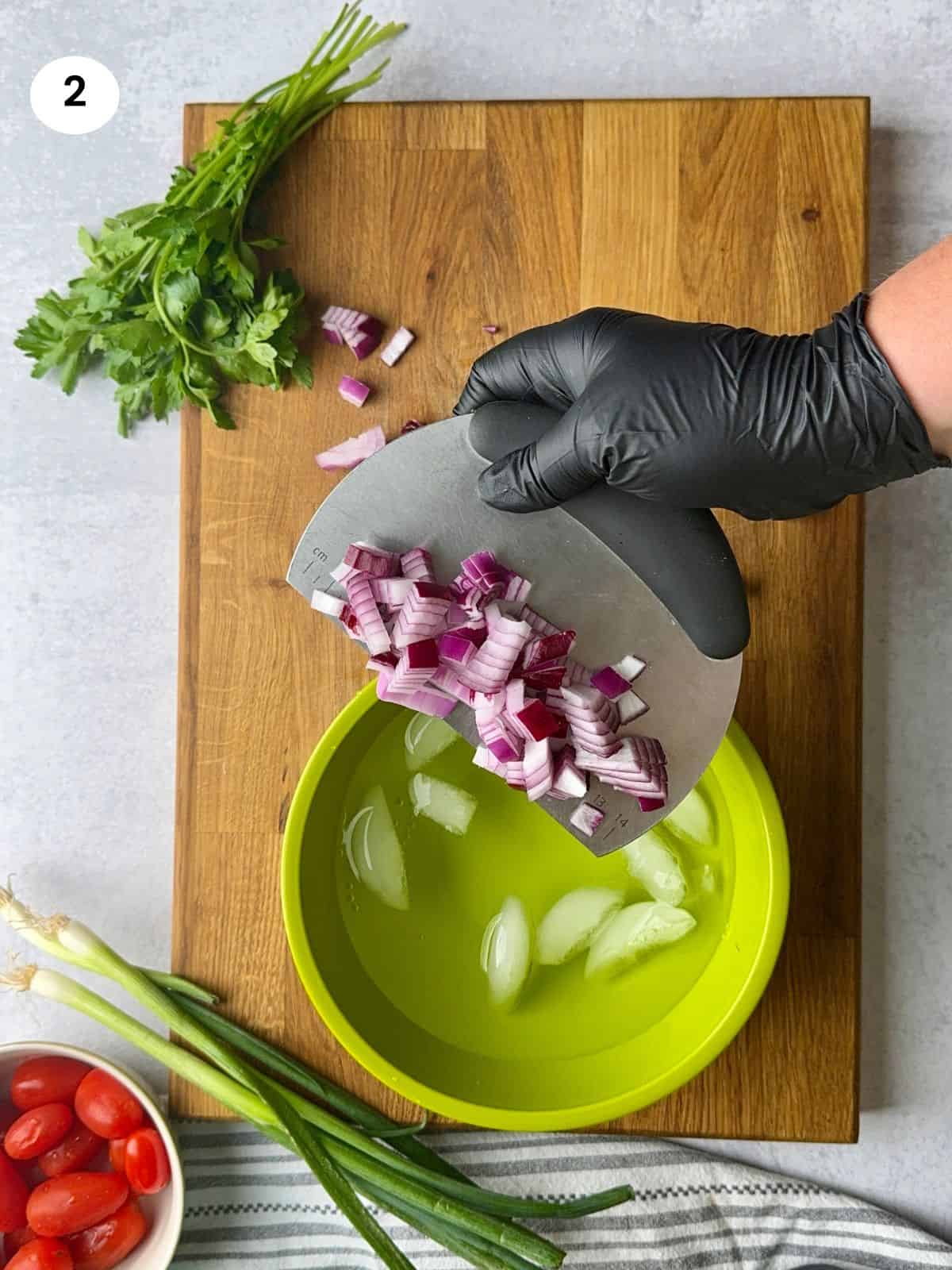 Placing the chopped red onion in cold water.