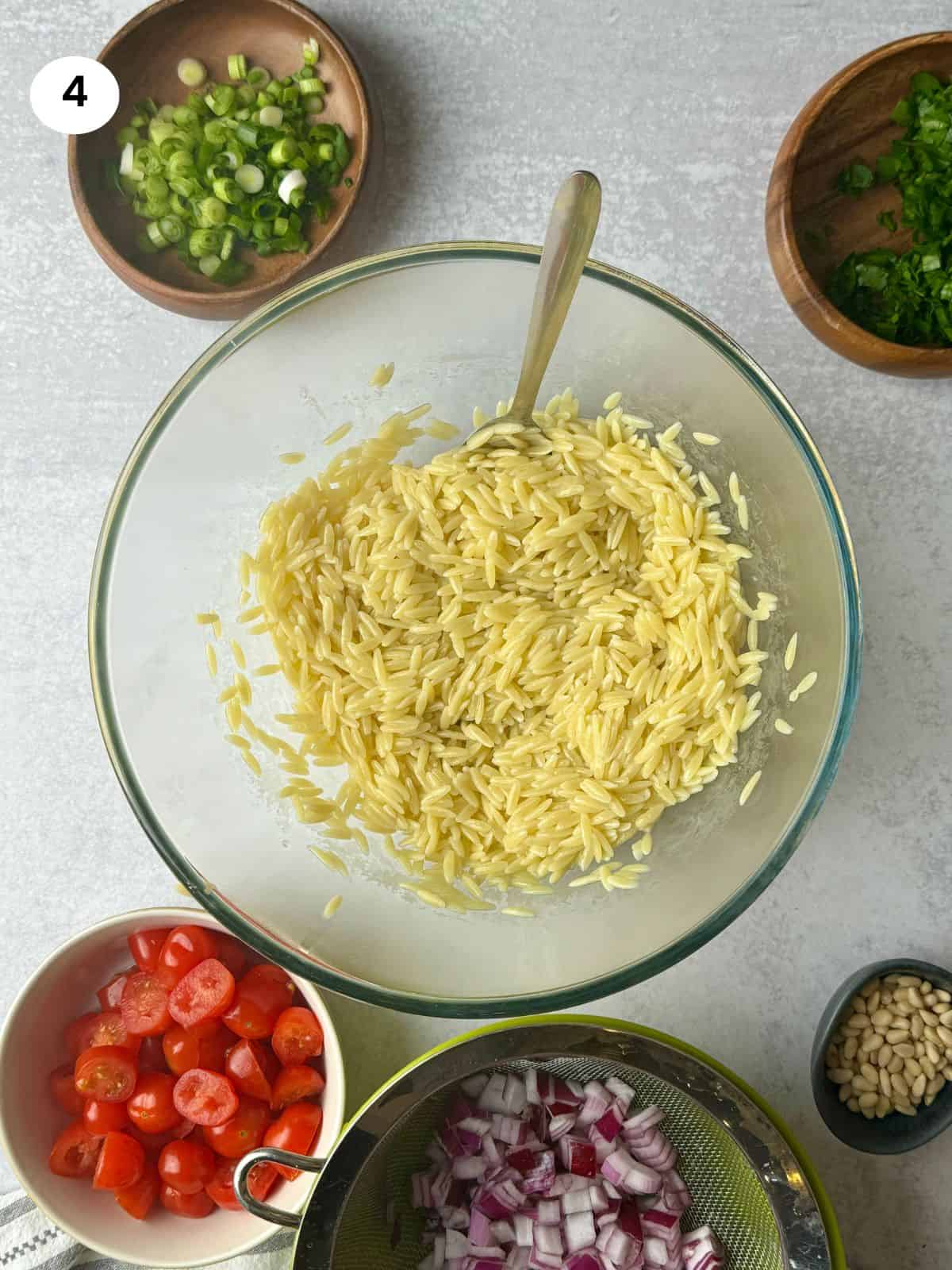 Orzo pasta in salad bowl with olive oil to prevent sticking.