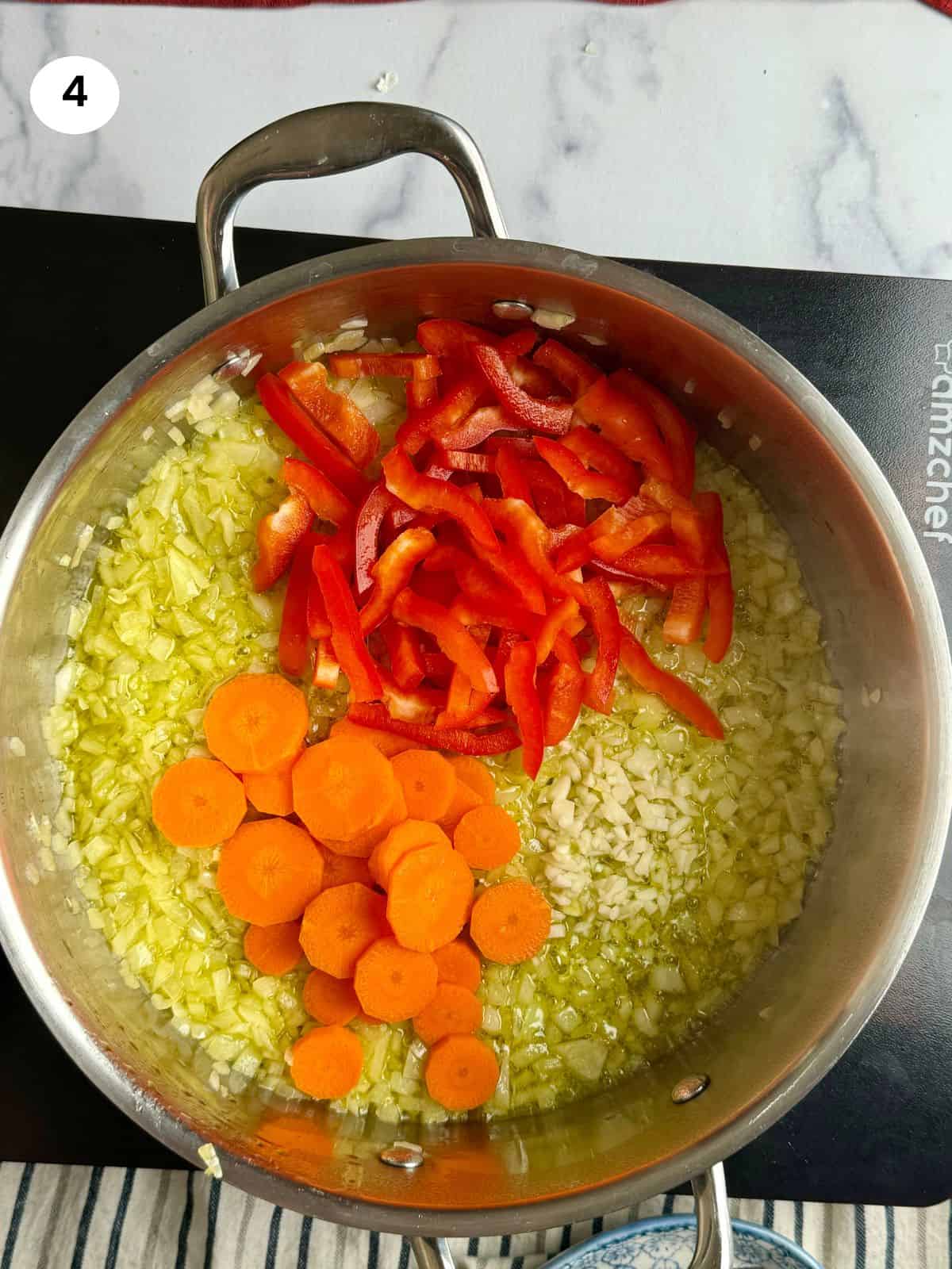 Adding the garlic, carrot and pepper slices to the pan.