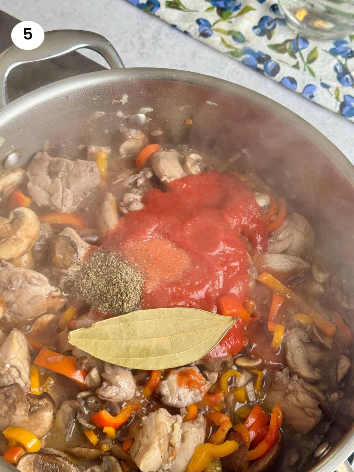 Tomatoes and seasoning added to the pan.