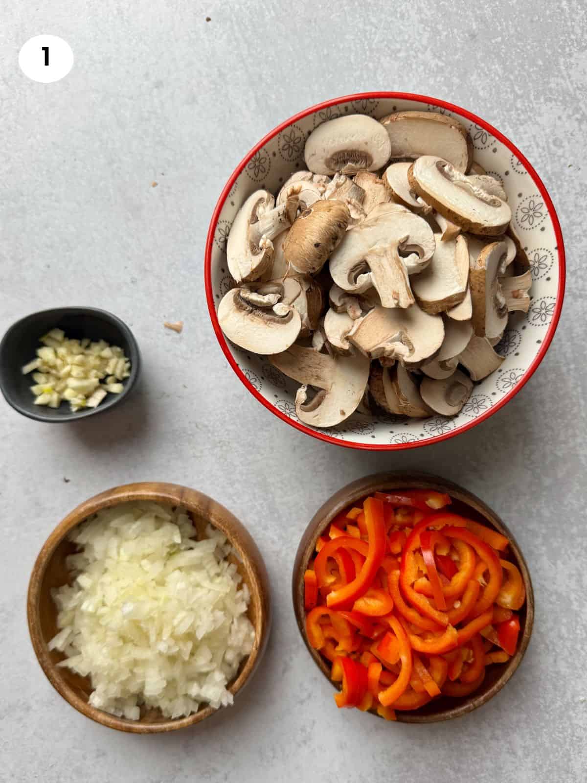 Chopped mushrooms, peppers, onion and garlic cloves.