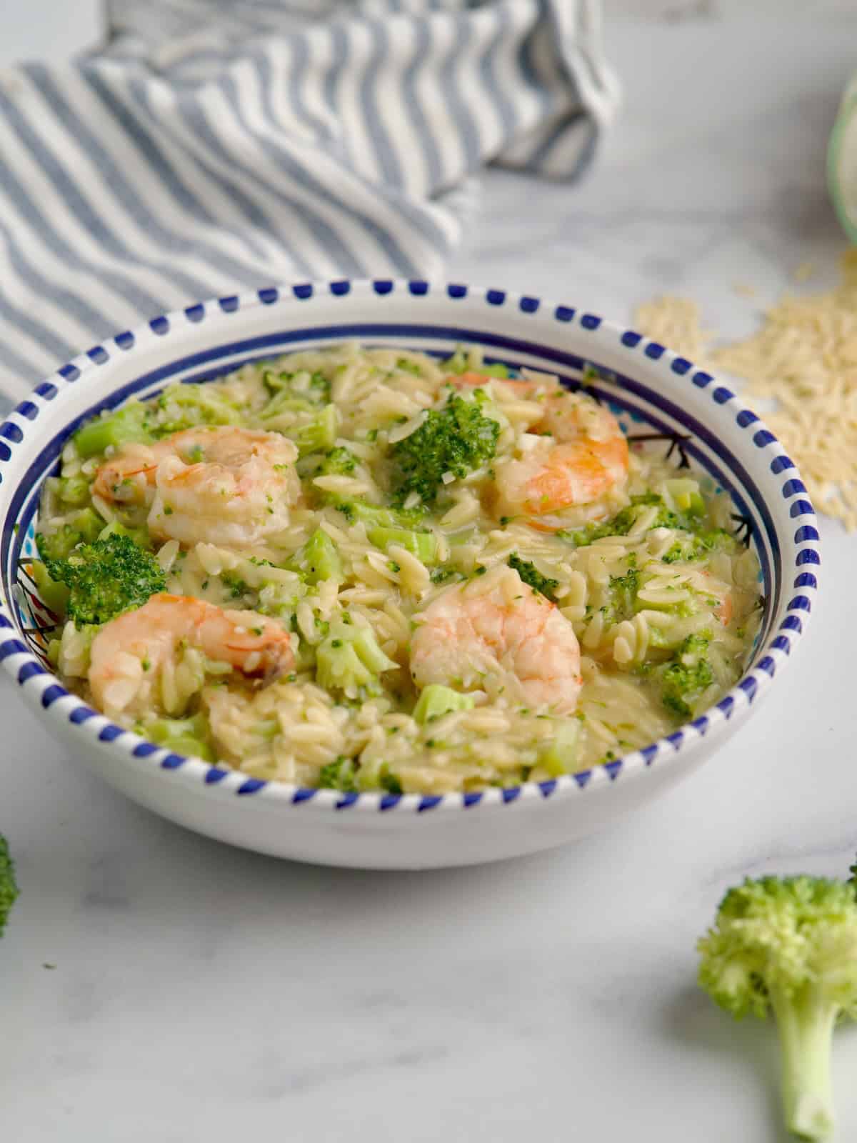 Served broccoli, shrimp and orzo pasta in a blue bowl.