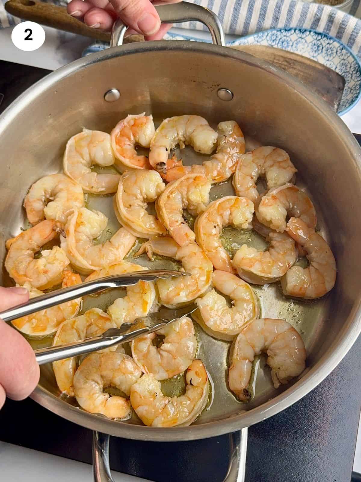 Sauteing the shrimp until pink.