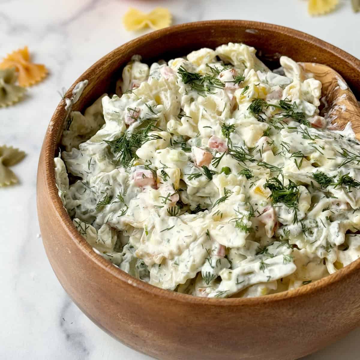 Pasta salad served in a wooden bowl.