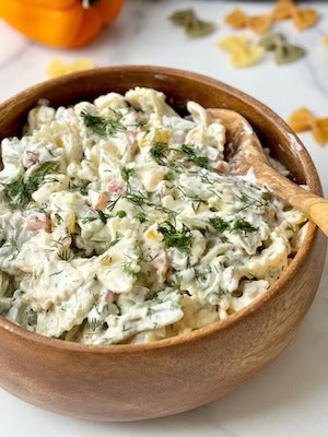 Pasta salad served in a wooden bowl.