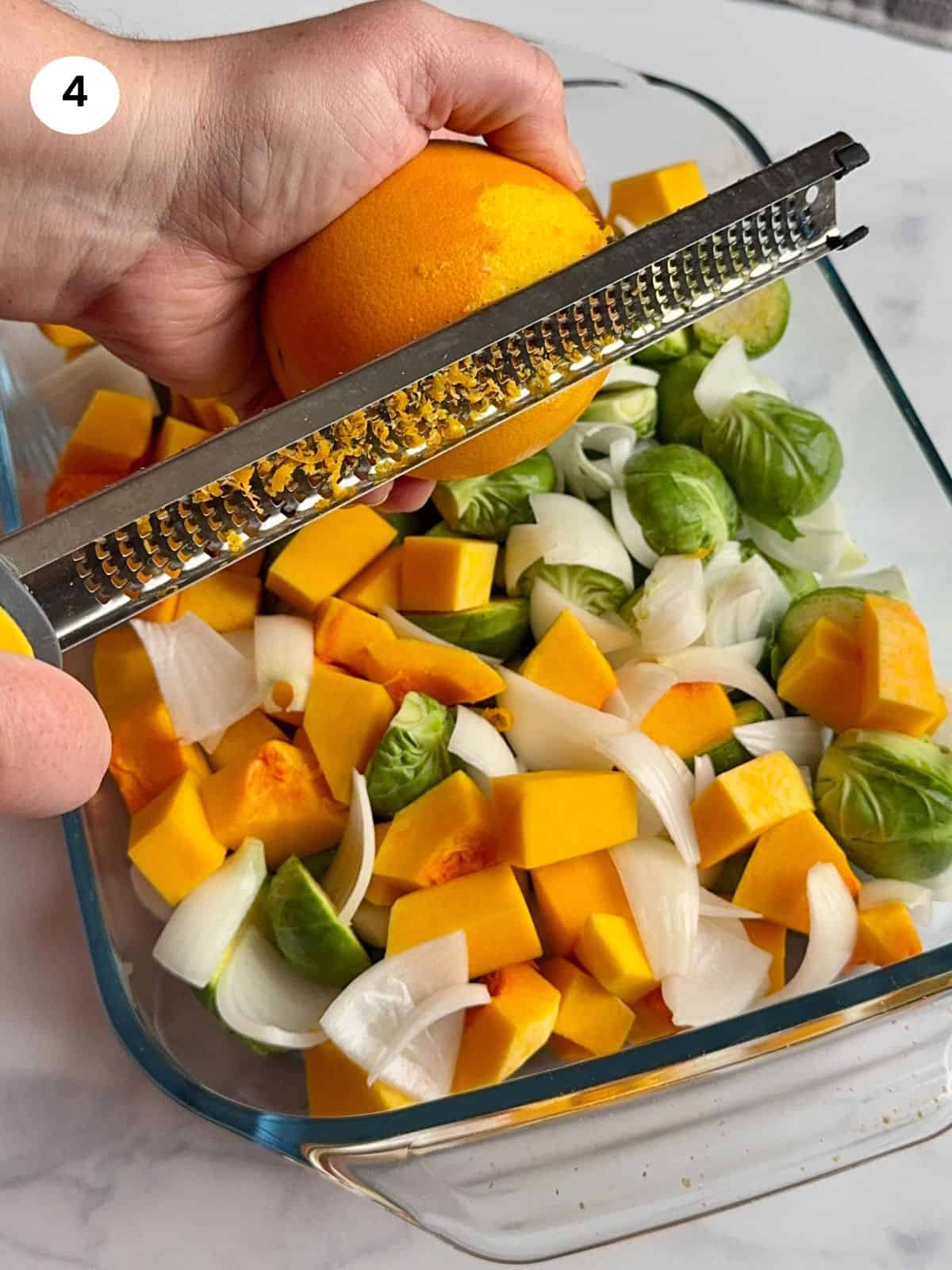 Zesting an orange on top of the casserole dish.