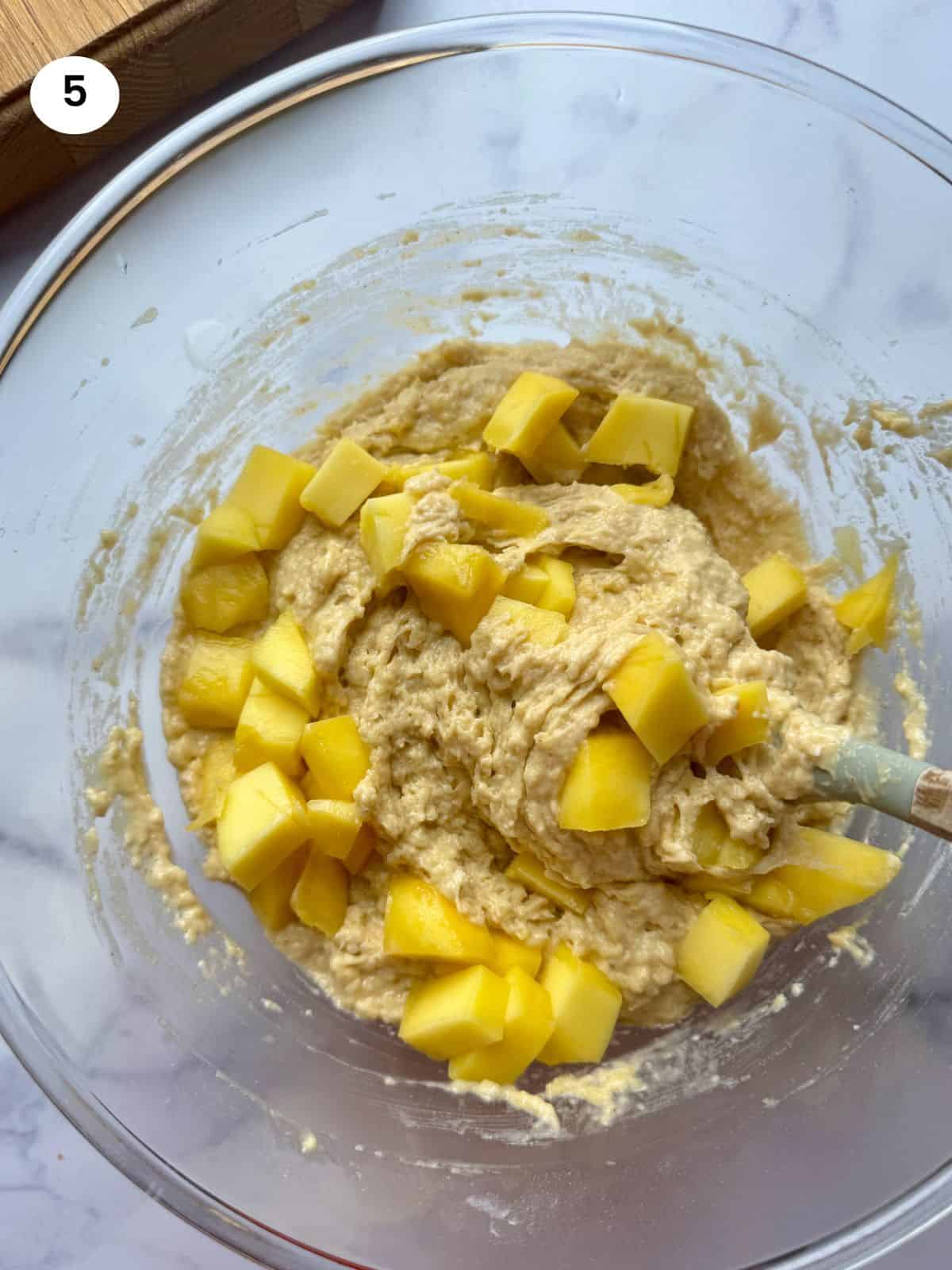 Adding the mango chunks to the batter.