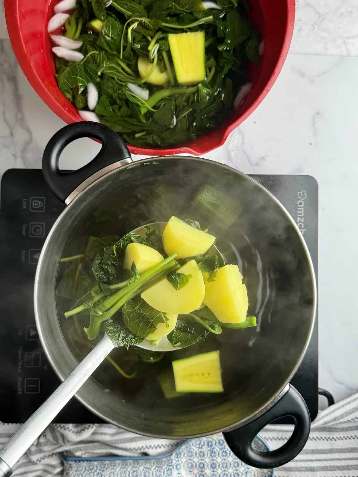 Putting cooked greens and veggies in a bowl filled with cold water.